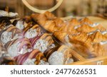 A variety of fresh pastries in the bakery window. Sweet big Croissant on shelf show for sale. Close up of appetizing golden croissants in cafe on shop window.