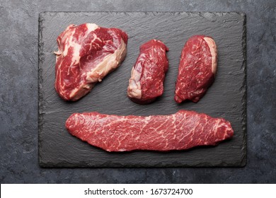 Variety of fresh raw beef steaks on stone plate. Top view flat lay - Shutterstock ID 1673724700