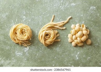 Variety of fresh raw uncooked homemade pasta. Spaghetti, tagliatelle and shells pasta on a floured work surface.  - Powered by Shutterstock