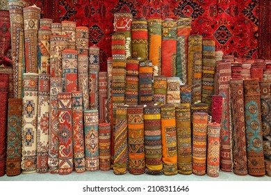 Variety Of The Gorgeous Oriental Carpets In Traditional Carpet Store In Middle East. Pile Of Beautiful Handmade Carpets On The Traditional Middle East Market Bazaar. Turkish Colourful Carpets