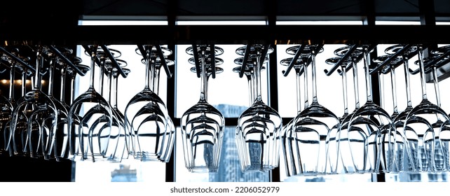 Variety Kinds Of Empty Wine And Cocktail Glasses Hanging Upside Down In Bar Rack At Luxury Rooftop Bar And Restaurant With Blurred City Scape Background