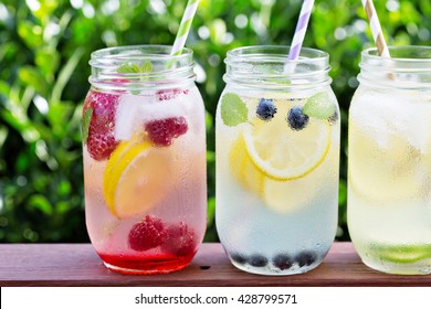 Variety of lemonade in mason jars with berries and fruits on the front porch