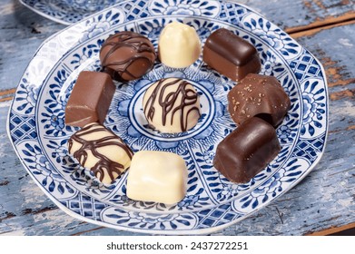 Variety of luxury belgian chocolate pralines bonbons on blue china porcelain plate, tea time, close up