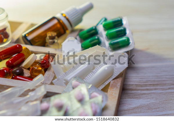 a variety of medicines in a wooden box with\
dividers on the table, local\
focus