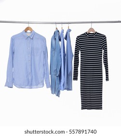 Variety of men's clothes shirts with woman sundress on hangers

