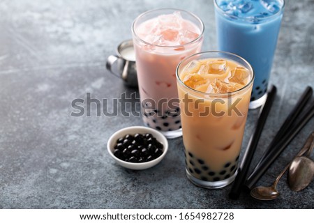 Variety of milk bubble tea in tall glasses, strawberry, butterfly tea and black