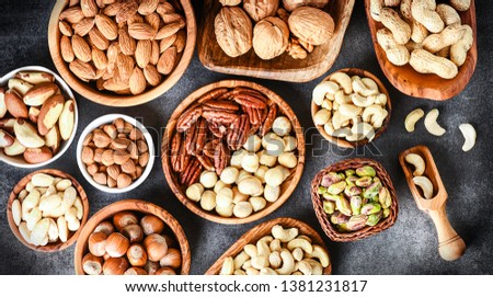 A variety of nuts in wooden bowls from top view. Walnuts, cashew, almond, pistachio, pecan, hazelnut, macadamia nut selection. Healthy super food.
