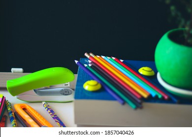 A variety of office accessories on the background of a dark school blackboard. On the board there is room for a copy space.