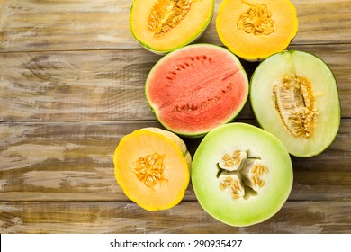 Variety of organic melons sliced on wood table.
