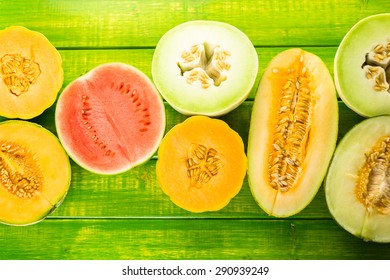 Variety of organic melons sliced on wood table.