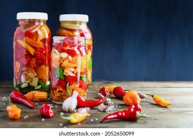 Variety Of Peppers, Spices And Garlic In A Mason Jars Fermenting, A Rich Source Of Probiotics, To Make Homemade Hot Sauce Over A Rustic Wood Background Table. Selective Focus With Blurred Background.