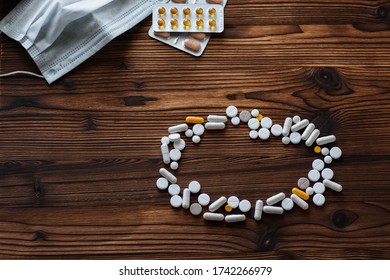 A variety of pills, tablets in a bister and medical mask on a wooden background. The concept of epidemic and protection against virus. - Shutterstock ID 1742266979