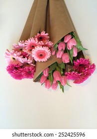 Variety Of Pink Flowers Wrapped In Brown Paper