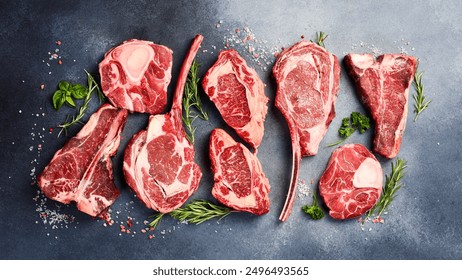 Variety of raw beef meat Prime steaks for grilling with seasoning: Tomahawk steak, Ribeye, T-bone and Ossobuco steak. Meat background.