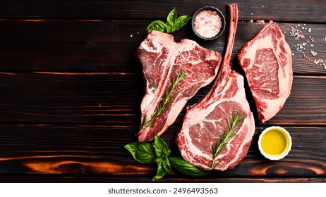 Variety of raw beef meat steaks for grilling with seasoning: Tomahawk steak, Ribeye, Ossobuco and T-bone steak, on a wooden brown background. - Powered by Shutterstock