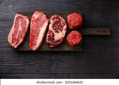 Variety of Raw Black Angus Prime meat steaks Blade on bone, Striploin, Rib eye, Tenderloin fillet mignon on wooden board copy space - Shutterstock ID 1031664631
