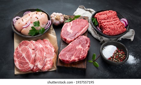 Vielfalt an Rohfleisch mit Würzmittel auf dunklem Hintergrund. 