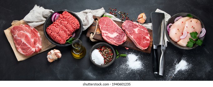 Variety of raw meat  with seasoning  on dark background. Top view, panorama, banner
