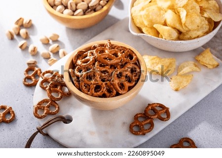 Variety of salty snacks on the table with pretzels, pistachios and potato chips, snacks that go well with beer