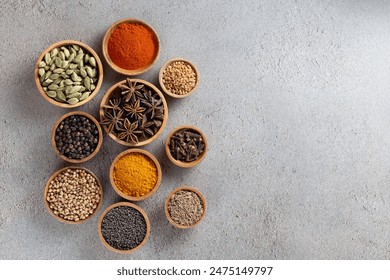 A variety of spices in wooden bowls on a gray background with copyspace top view, vibrant colors and textures. - Powered by Shutterstock