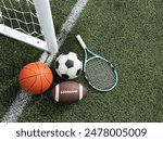 A variety of sports equipment including an american football, a soccer ball, a tennis racket, a tennis ball, and a basketball