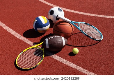 A variety of sports equipment including an american football, a soccer ball, a tennis racket, a tennis ball, and a basketball - Powered by Shutterstock