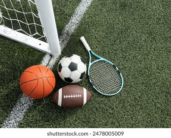 A variety of sports equipment including an american football, a soccer ball, a tennis racket, a tennis ball, and a basketball - Powered by Shutterstock