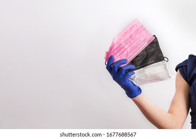 Variety Of Surgical Medical Masks. 
Doctor Holds A 
Colored Medical Masks In His Hand. Rubber Surgical Gloves. Large Assortment. Face Mask. Virus And Epidemic Protection Concept