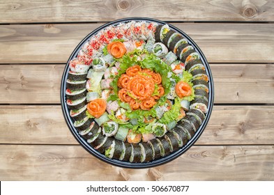  Variety of sushi rolls and sashimi on a plastic platter against wooden background