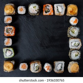 A variety of sushi with wooden desk on black slate background. Asian food frame. Dinner party.Top view. Copy space, overhead, flat lay