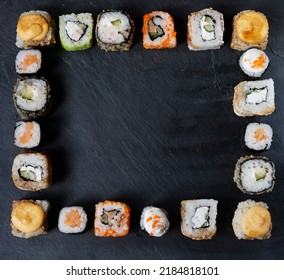 A Variety Of Sushi With Wooden Desk On Black Slate Background. Asian Food Frame. Dinner Party.Top View. Copy Space, Overhead, Flat Lay