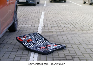 Variety Tools For Repairing And Diagnostic A Car. Tool Set In Box Near The Orange Auto In Parking Lot. Automobile Maintenance Concept.