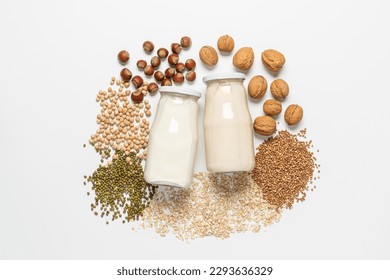 Variety of vegan plant based milk in glass bottles. Top view of lactose free milk based on nuts, legumes, oatmeal on white background - Shutterstock ID 2293636329