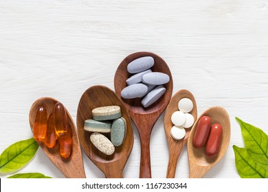 Variety of vitamin pills in wooden spoon on white background with green leaf, supplemental and healthcare product, flat lay surface - Shutterstock ID 1167230344