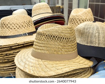 Variety of woven straw hats displayed outdoors on a market stall.