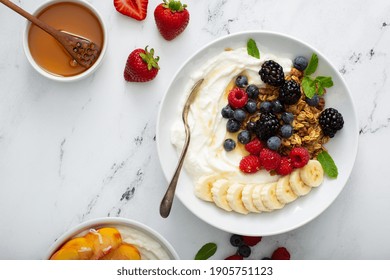 Variety Of Yogurt Bowls With Strawberry And Plain Yogurt, Fruit And Granola