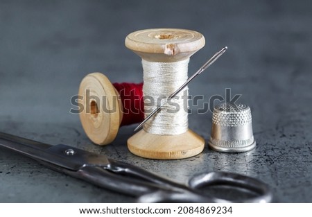 Various accessories for needlework. A set of sewing tools, spools of thread, fabrics, scissors and a thimble on an old surface. Retro style
