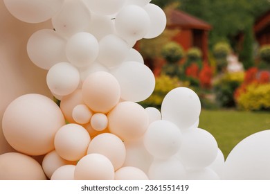 Various air balloons of different pastel colours and sizes. Details of creative gender neutral babyshower or birthday party decoration outdoors. Festive photo zone arch kit.
