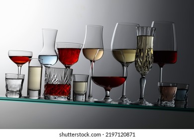 Various Alcoholic Drinks In A Bar On A Tilted Glass Shelf.