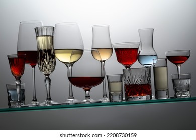Various Alcoholic Drinks In A Bar On A Tilted Glass Shelf.