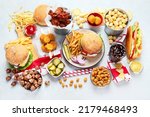 Various of american food, French fries, hamburgers, nuggets, hotdog, chips, popcorn, sauces on a white background, top view.