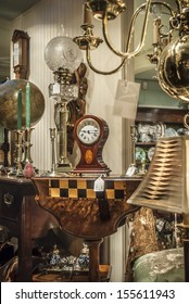 Various Antiques For Sale Viewed Through A Shop Window.