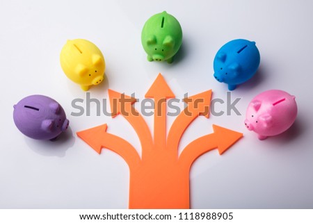 Various Arrow Symbols Showing Direction Towards Colorful Piggybanks Over White Background