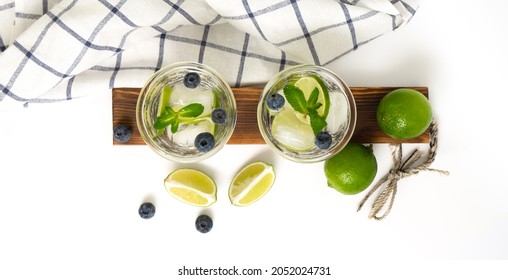 Various berry lemonade or mojito cocktails, fresh iced lemon lime blueberry infused water, summer healthy detox drinks isolated on white top view