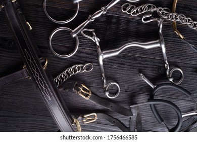  various bits  with mouthbridle and spurs on black wooden  background. flat lay