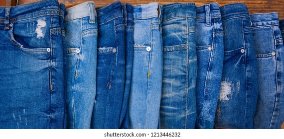 Various blue jeans on wooden background . Stack of jeans
