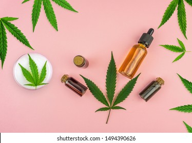 Various bottles with Full spectrum Cannabidiol CBD oils, gel lotion and Cannabis leaf on pastel pink background