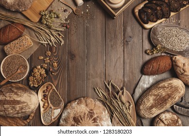 Various bread selection flat-lay. Top view of rye, wheat and multigrain rustic bread loaves over dark wooden vertical planks background with a blank copyspace for text in the middle of circle