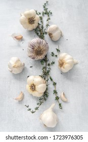 Various bulbs of garlic on top of sprigs of thyme.
