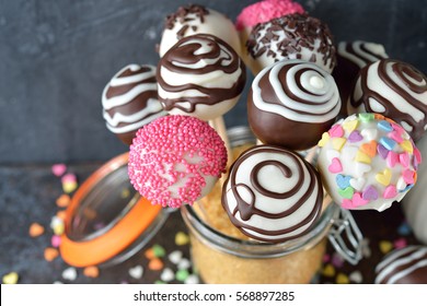 Various cake pops decorated with white and dark chocolate on a brown background - Powered by Shutterstock